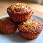 A stack of three golden brown Cottage Cheese Banana Muffins resting on a white plate.