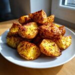 A mound of golden, crispy Oven-Baked Potato Wedges seasoned with herbs, served on a white plate.