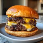 Close-up of a delicious double Smash Burger featuring two thin, well-seared patties with melted American cheese on a toasted brioche bun.