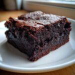Close-up of a rich, dark, fudgy slice of Protein Brownie on a white plate.