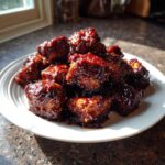 A mound of sticky, dark glazed Bbq Chicken Bites piled high on a white plate.