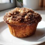 A single, perfectly baked Greek Yogurt Cinnamon Muffin topped with a thick cinnamon sugar streusel, resting on a white plate.