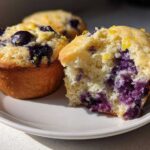 Close-up of a Lemon Blueberry Muffins, one broken open showing the moist crumb and burst blueberries inside.