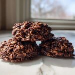 Close-up of three rich, fudgy No-Bake Chocolate Oatmeal Cookies stacked on a white marble surface.