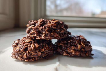 Close-up of three rich, fudgy No-Bake Chocolate Oatmeal Cookies stacked on a white marble surface.
