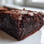 Close-up of a rich, dark chocolate slice of Protein Brownie showing a moist interior and shiny, cracked top.
