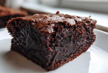 Close-up of a rich, dark chocolate slice of Protein Brownie showing a moist interior and shiny, cracked top.