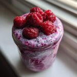 Close-up of Raspberry Chia Seed Pudding in a jar, topped with whole fresh raspberries.