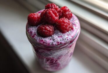 Close-up of Raspberry Chia Seed Pudding in a jar, topped with whole fresh raspberries.