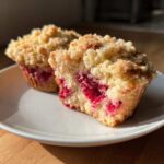 Close-up of a Raspberry Streusel Muffins cut in half, showing moist interior and thick crumb topping.