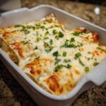 Close-up of baked Sour Cream Chicken Enchiladas covered in melted, slightly browned cheese and green onions.
