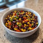 Close-up of vibrant Cowboy Caviar Dip featuring black beans, corn, and diced peppers in a white bowl.