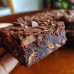 A close-up shot of a rich, fudgy slice of Kit Kat Brownie Bars showing melted chocolate chunks inside.