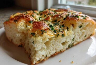 A thick slice of fluffy Garlic Parmesan Focaccia Bread topped with melted cheese and fresh parsley.