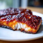 A close-up of a flaky, cooked salmon fillet topped with a thick, glossy Gochujang Honey Glazed Salmon sauce.