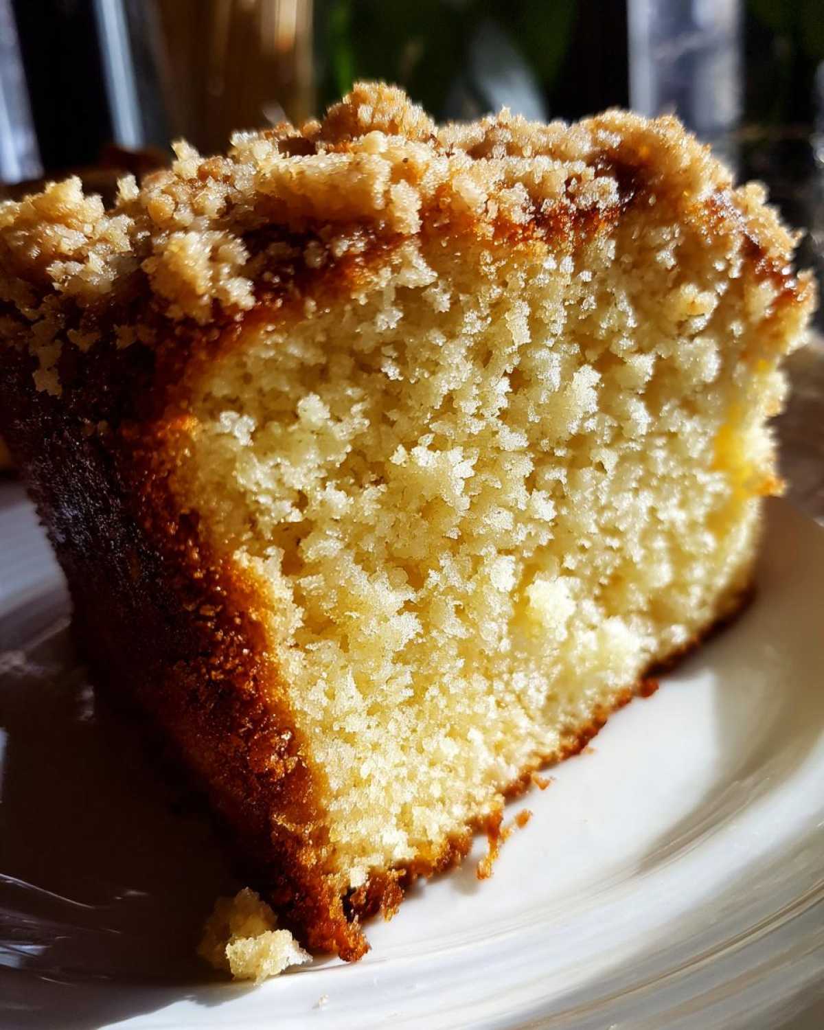 A close-up, sunlit slice of moist Lemon Coffee Cake with a thick, golden Lemon Crumb Topping.