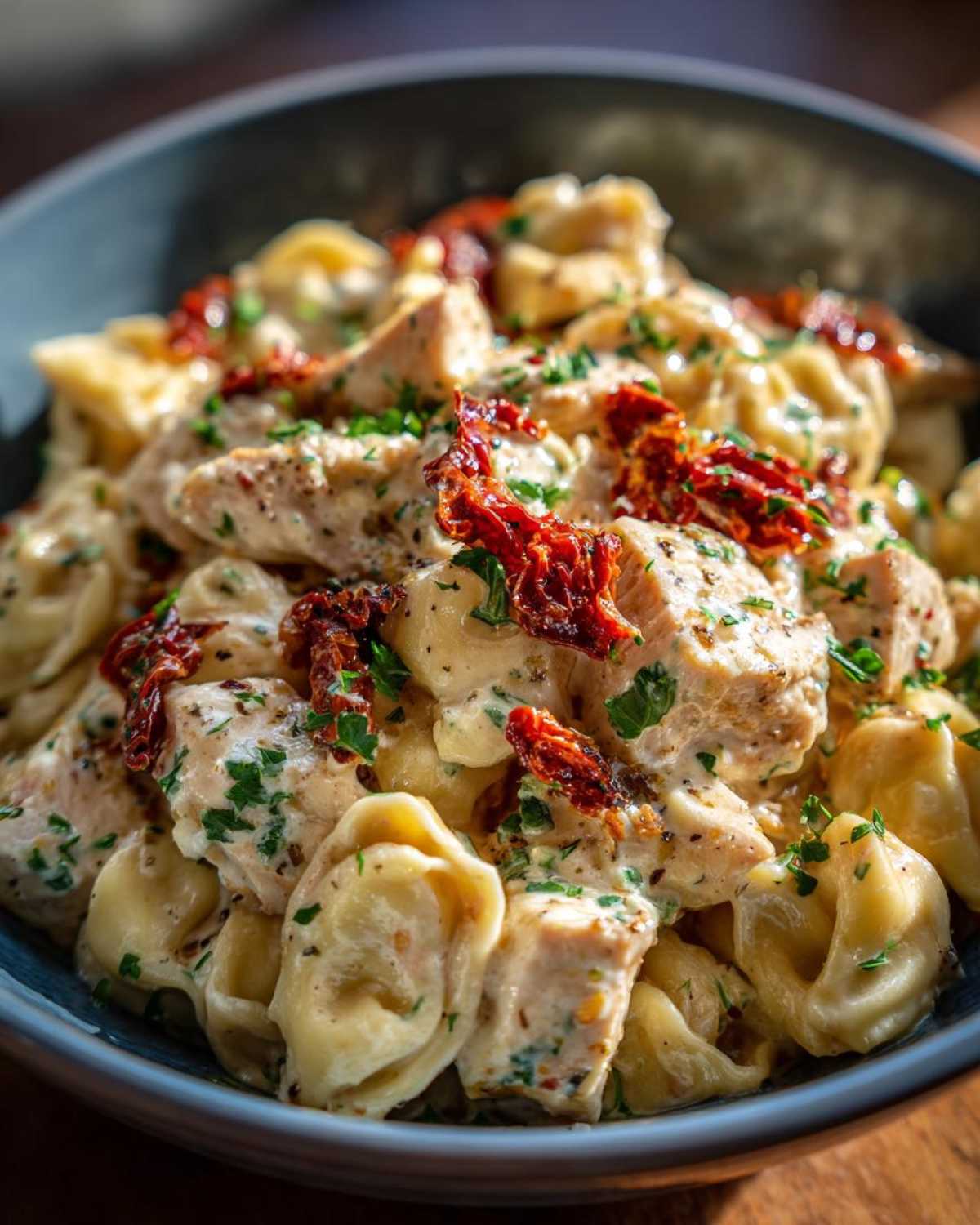 Close-up of Marry Me Chicken Tortellini pasta coated in a creamy sauce with chicken chunks and sun-dried tomatoes.