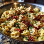 Close-up of Marry Me Chicken Tortellini covered in a creamy sauce, topped with sun-dried tomatoes and parsley.