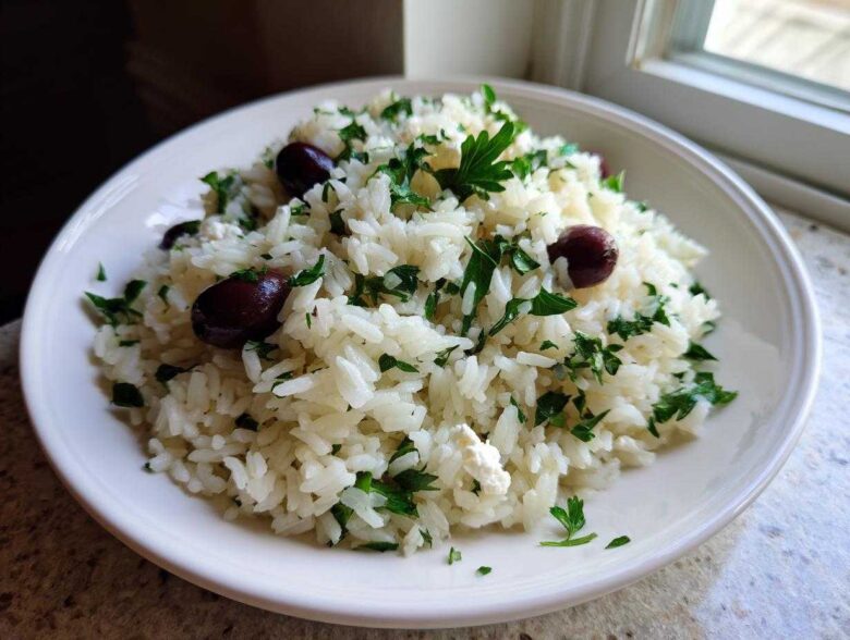 A white bowl filled with fluffy Mediterranean Rice mixed with chopped parsley, feta cheese, and Kalamata olives.
