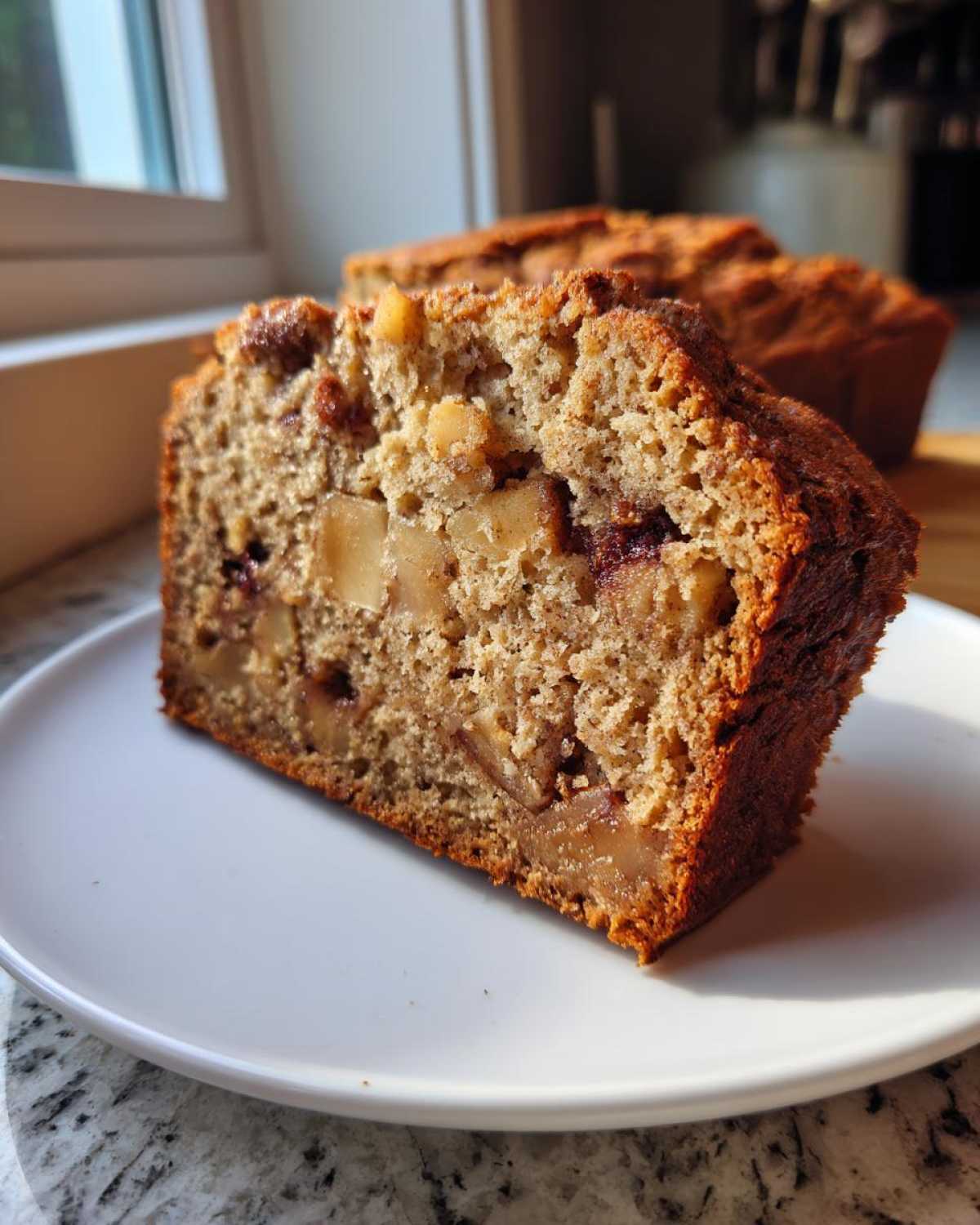 Close-up of a moist slice of Apple Cinnamon Bread showing chunks of apple and nuts inside.
