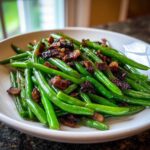 A close-up of bright green Sautéed Green Beans with Crispy Bacon served in a white bowl.