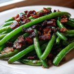 Vibrant green beans topped with crispy bacon pieces, ready to serve as Sautéed Green Beans with Crispy Bacon.